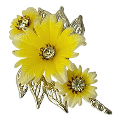 Vintage yellow celluloid floral brooch from the 1950s featuring three gradient yellow-to-white flowers with clear rhinestone centers, accented by light gold-tone openwork leaves.