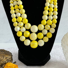 Vintage 1950s yellow three‑strand necklace with graduated cellulose acetate beads in solid and marbled tones, shown in various views to display bead details and overall design.