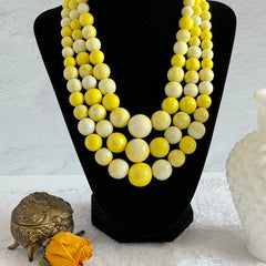 Vintage 1950s yellow three‑strand necklace with graduated cellulose acetate beads in solid and marbled tones, shown in various views to display bead details and overall design.