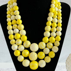 Vintage 1950s yellow three‑strand necklace with graduated cellulose acetate beads in solid and marbled tones, shown in various views to display bead details and overall design.
