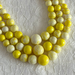 Vintage 1950s yellow three‑strand necklace with graduated cellulose acetate beads in solid and marbled tones, shown in various views to display bead details and overall design.