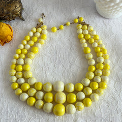 Vintage 1950s yellow three‑strand necklace with graduated cellulose acetate beads in solid and marbled tones, shown in various views to display bead details and overall design.