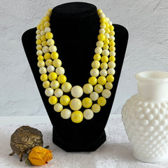 Vintage 1950s yellow three‑strand necklace with graduated cellulose acetate beads in solid and marbled tones, shown in various views to display bead details and overall design.