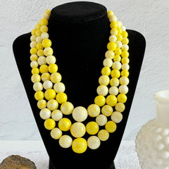 Vintage 1950s yellow three‑strand necklace with graduated cellulose acetate beads in solid and marbled tones, shown in various views to display bead details and overall design.