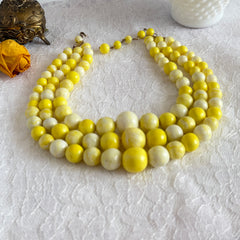 Vintage 1950s yellow three‑strand necklace with graduated cellulose acetate beads in solid and marbled tones, shown in various views to display bead details and overall design.